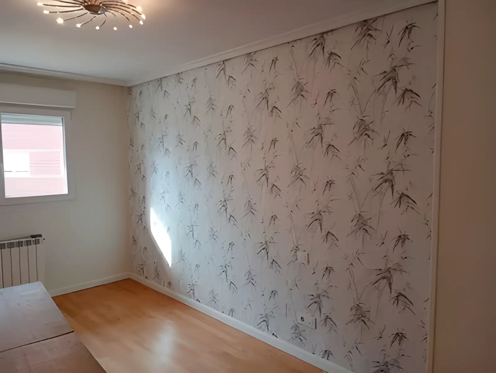 Pintores en Roquetas de Mar colocando papel pintado en pared de acento de habitación luminosa