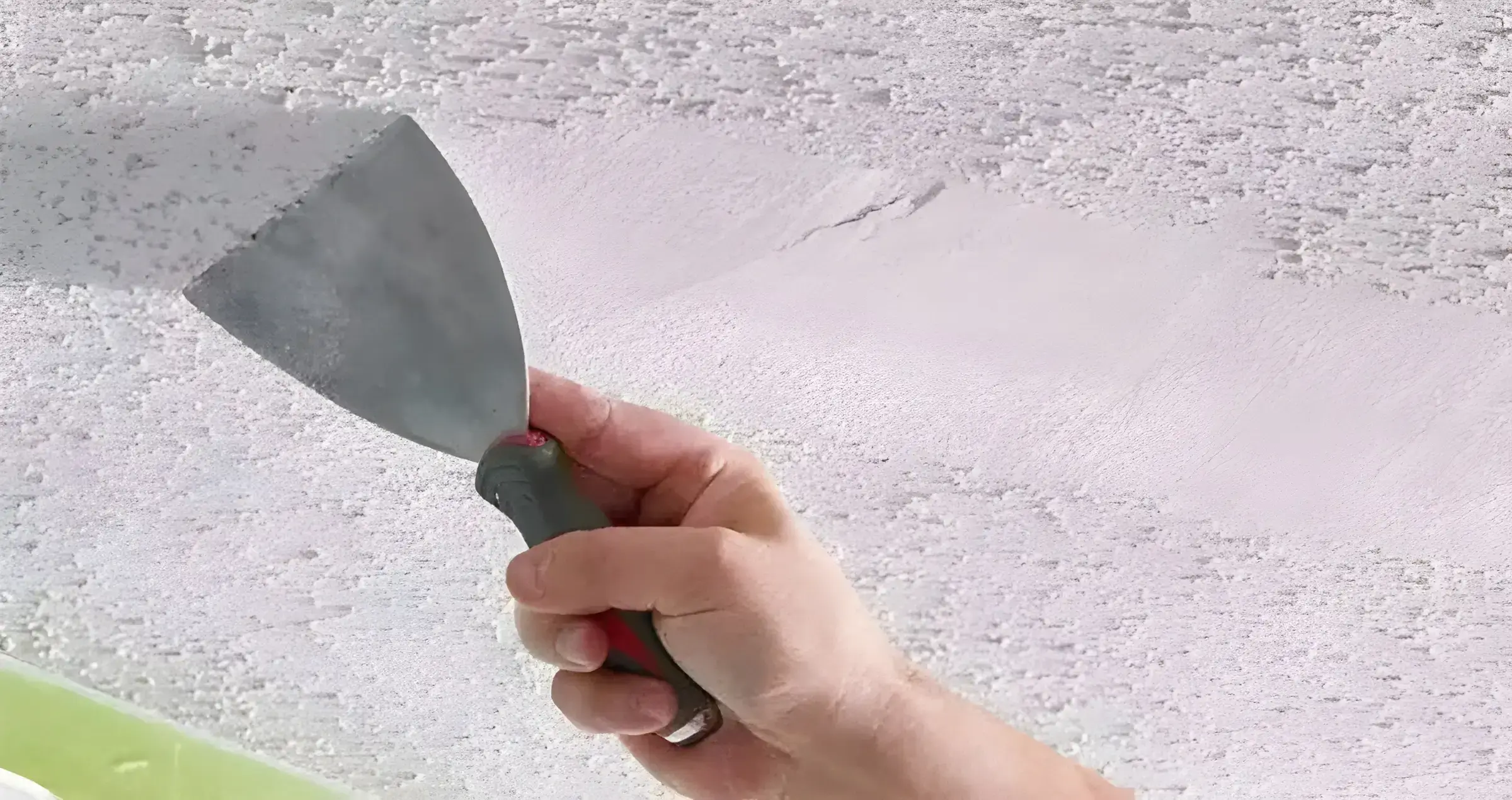 Pintores en Roquetas de Mar eliminando el gotelé con espátula para dejar la pared lisa